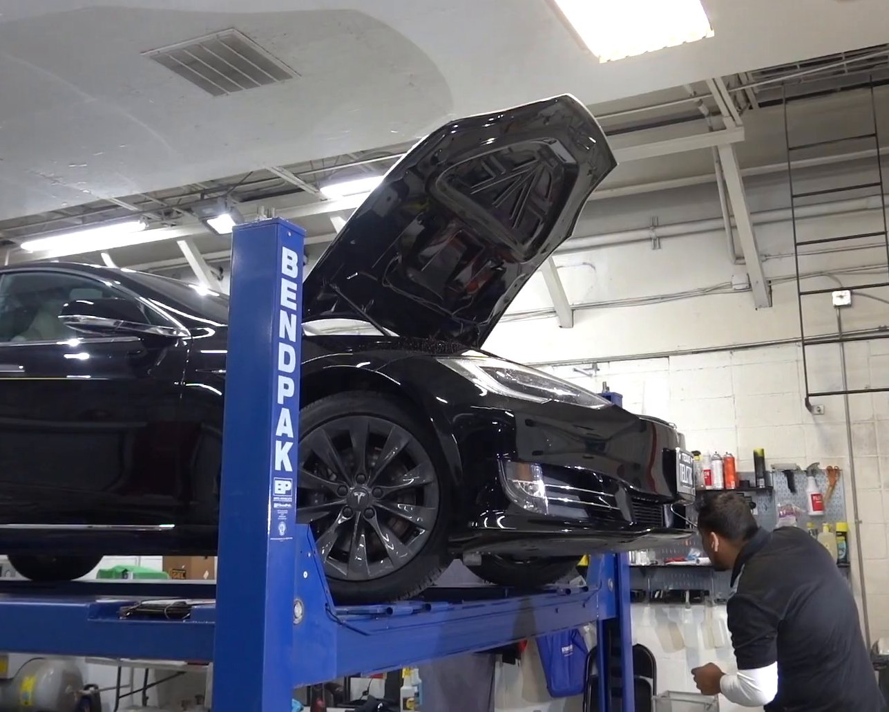 Black Tesla Model S on the lift with the frunk open for front-end collision repair at EVS Motors in Houston