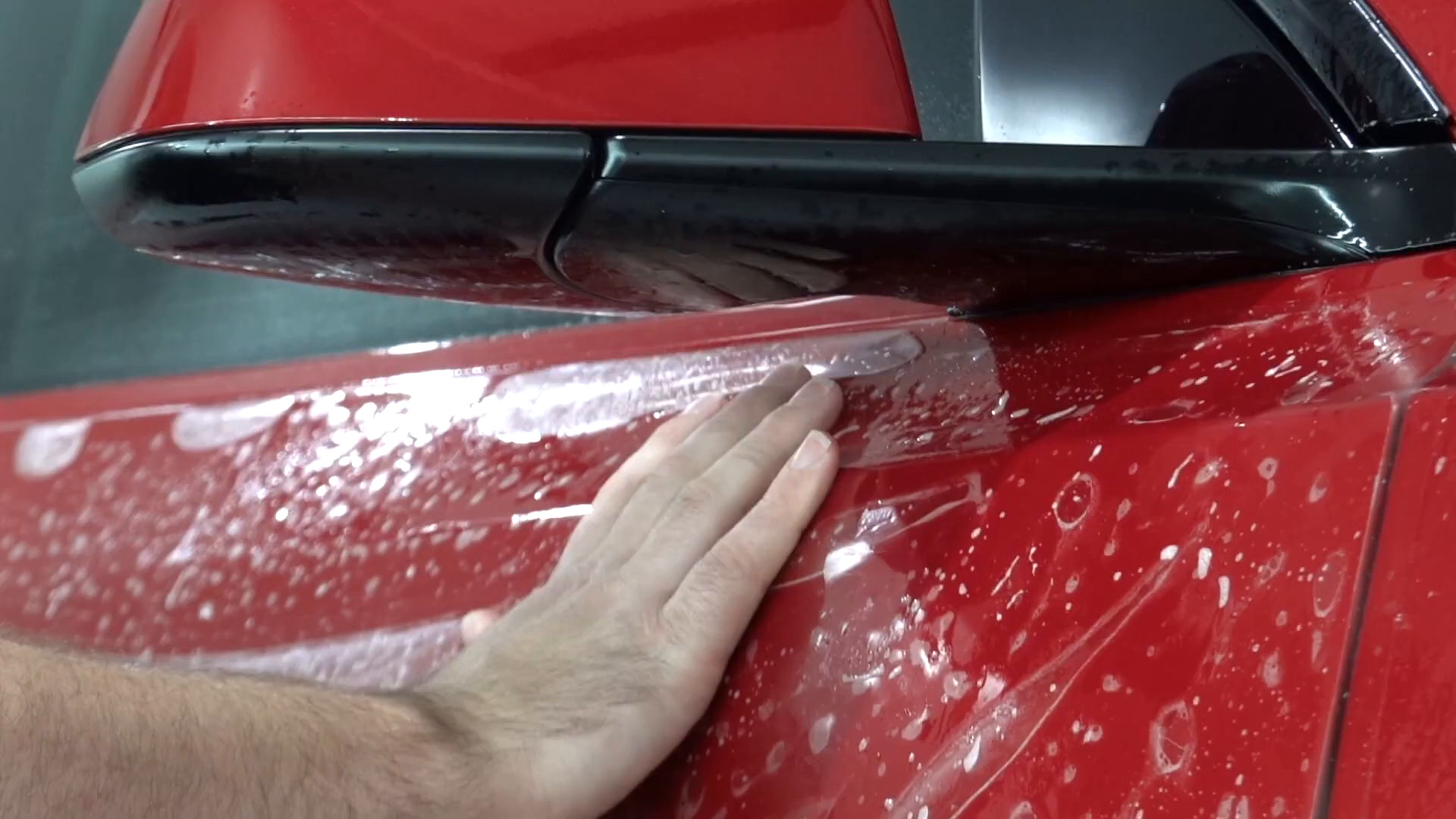 Installer squeegeeing paint protection film on a Tesla Model Y at EVS Motors